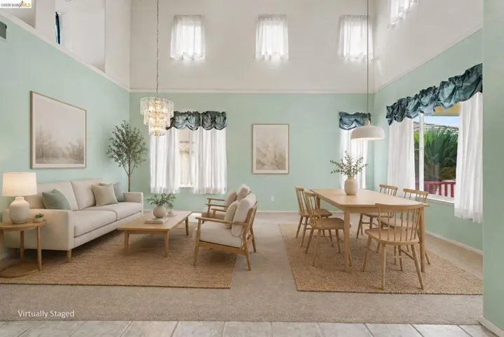 Spacious living area featuring high vaulted ceilings, multiple windows, a tiered chandelier, and recessed upper windows