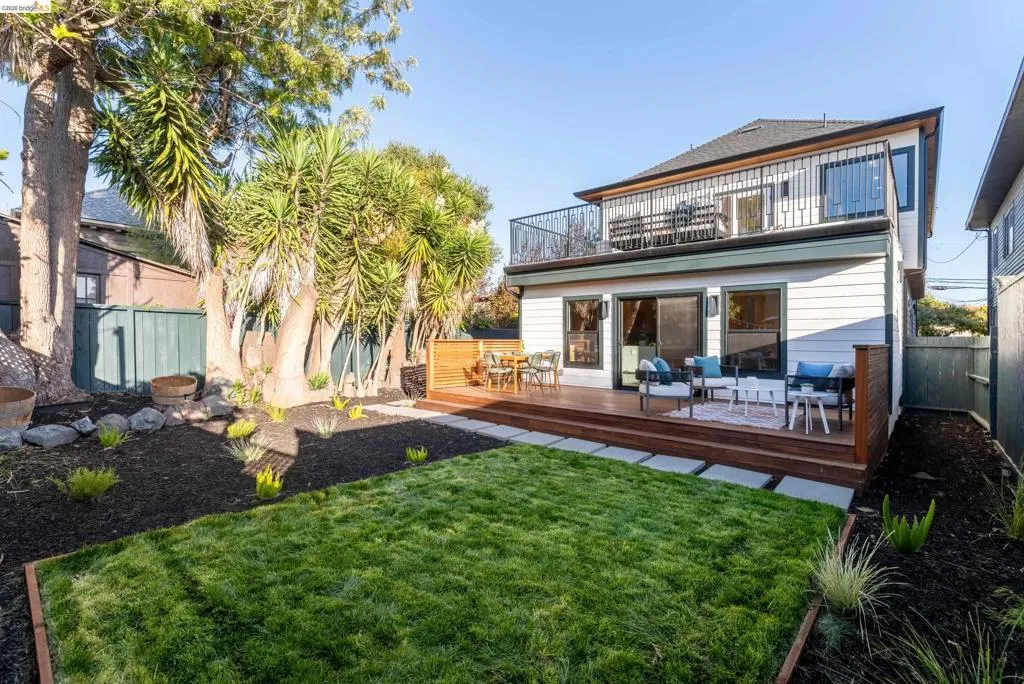 Expansive backyard featuring a manicured lawn, multi-level wood deck, and mature landscaping