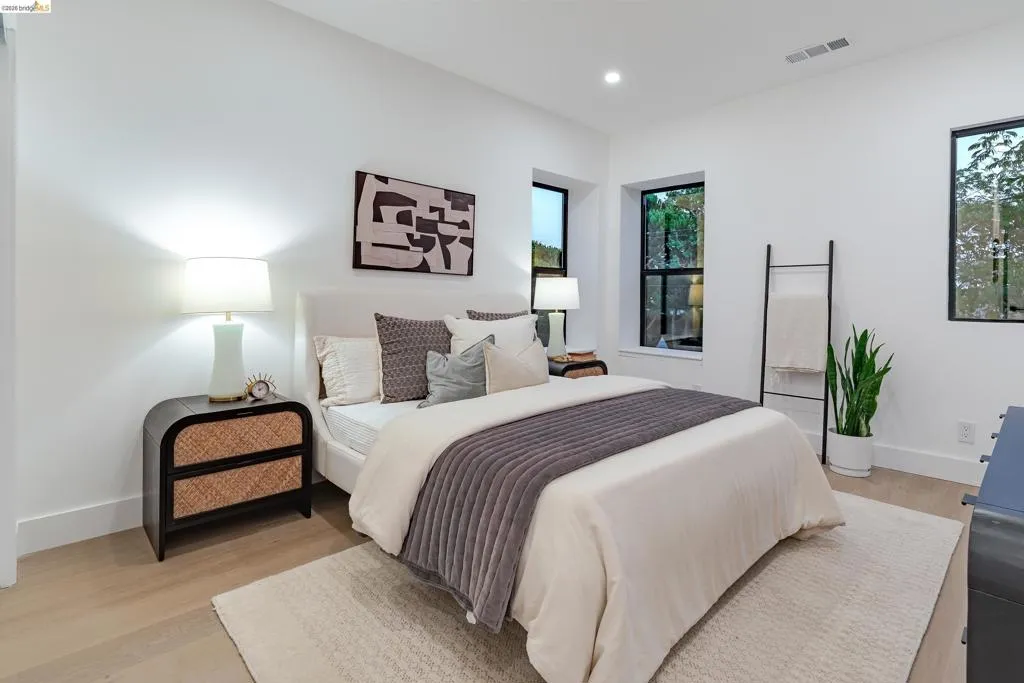 Light-filled room featuring white walls, recessed lighting, and wood-finish flooring