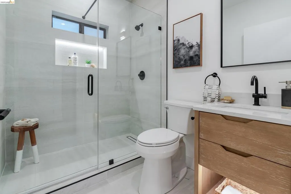 Contemporary bathroom featuring a frameless glass shower enclosure with a built-in niche and transom window