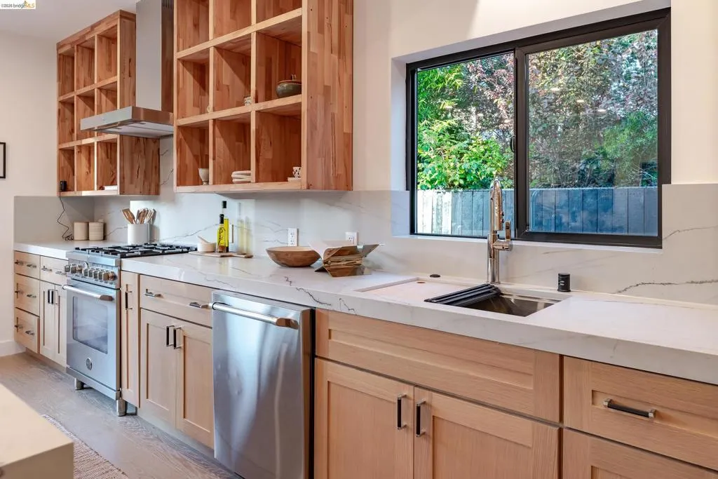 Modern kitchen featuring light wood cabinetry, stainless steel appliances, and white countertops with matching backsplash