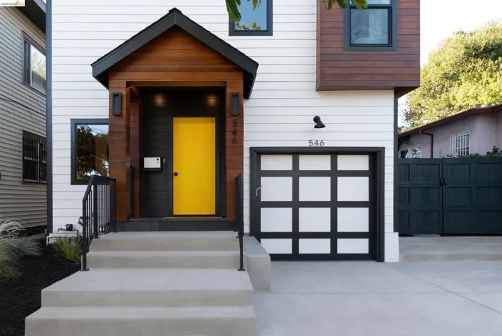 Modern facade featuring white horizontal siding, dark wood paneling, and a bright yellow entry door