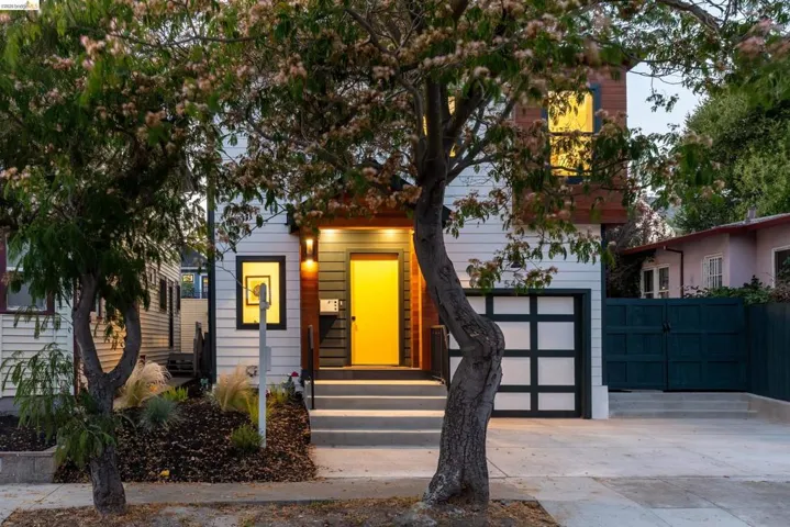 Contemporary facade featuring white siding with wood-tone accents, a vibrant yellow entry door, and a paneled garage door