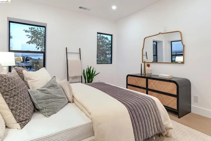 Bright room featuring a contemporary dresser with woven drawer fronts, a decorative mirror, and light wood-finish flooring