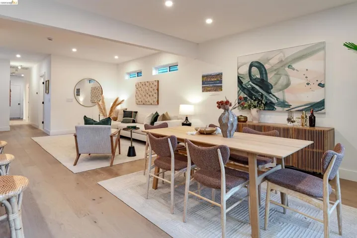 Open-concept living and dining area featuring light wood-finish flooring, recessed lighting, and white walls