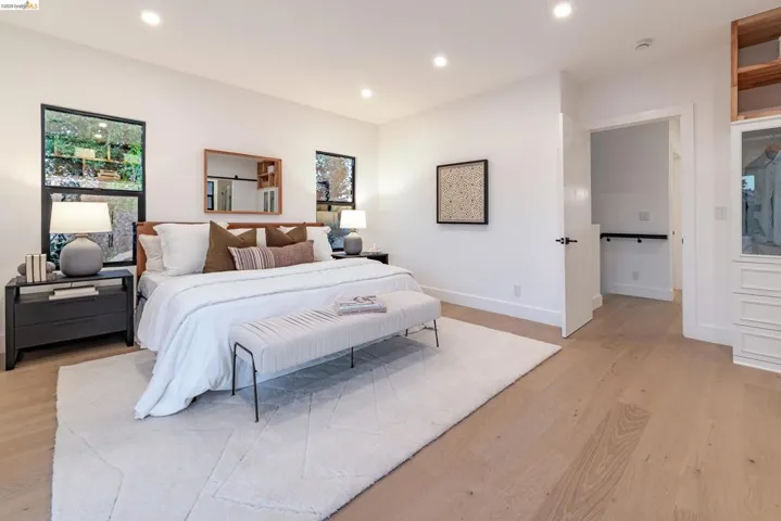 Spacious room featuring light wood-finish flooring, recessed lighting, and a white color palette