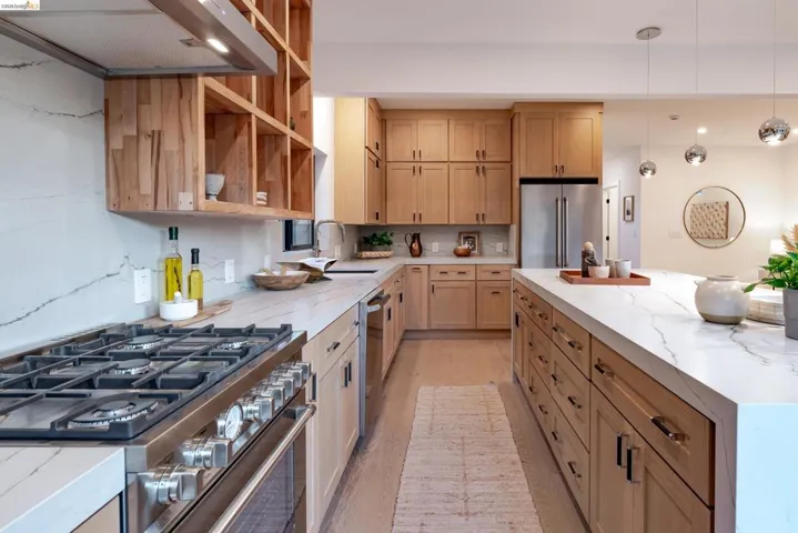 Kitchen featuring a stainless steel range with multiple burners, light wood cabinetry, and white countertops with visible veining