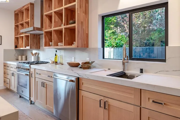 Modern kitchen featuring light wood cabinetry, stainless steel appliances, and white countertops with matching backsplash
