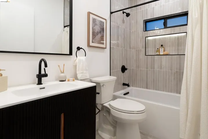 Bathroom featuring a white bathtub, vertical tile shower surround, and a recessed shower niche with integrated lighting