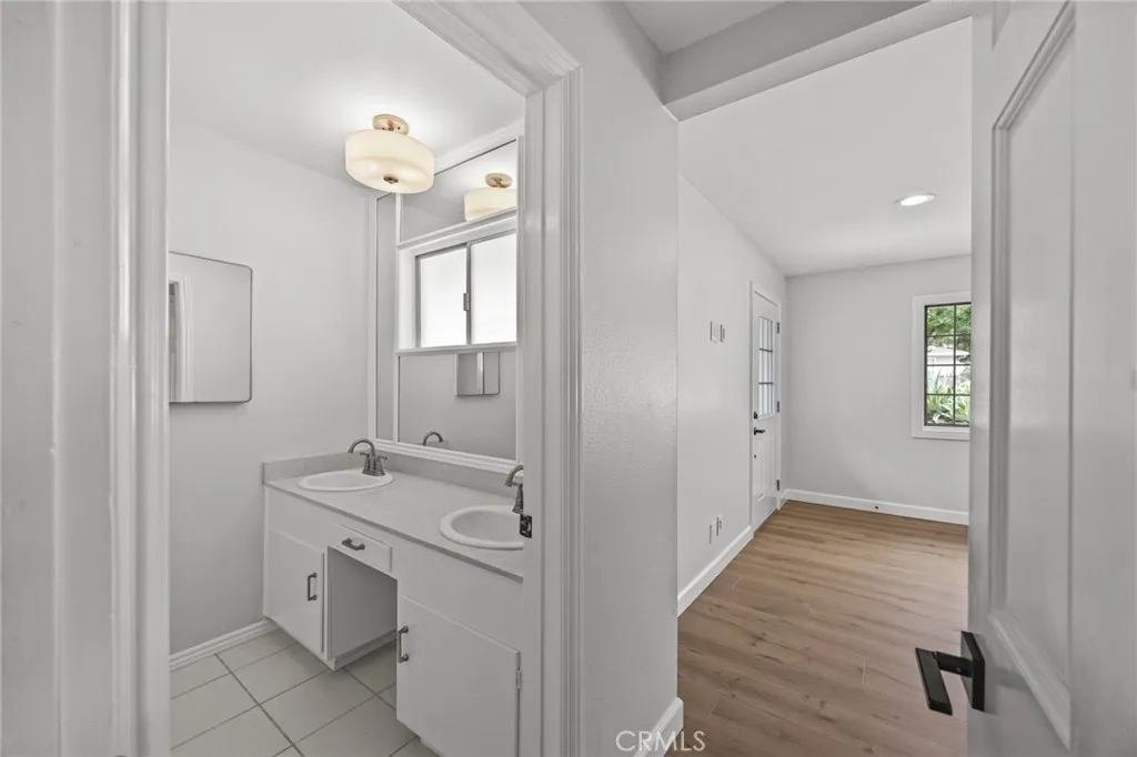Entrance to secondary suite showing private bathroom with dual sink vanity and walk-in shower