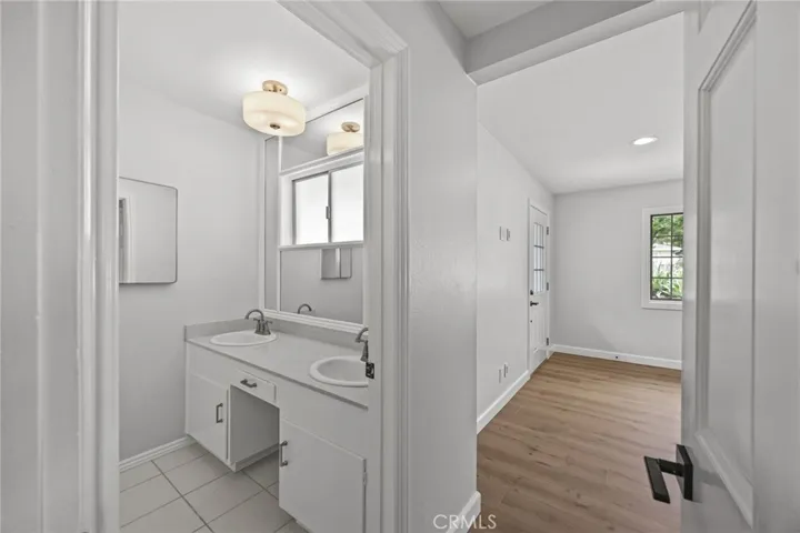 Entrance to secondary suite showing private bathroom with dual sink vanity and walk-in shower