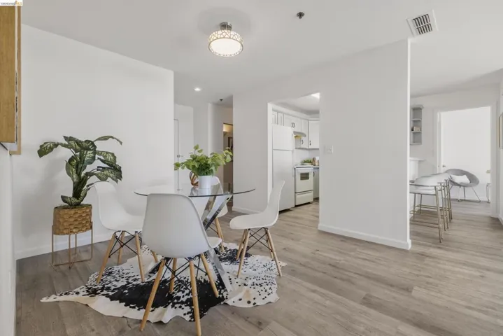 Open-concept living area with wood-finish flooring, white walls, and a recessed ceiling light fixture