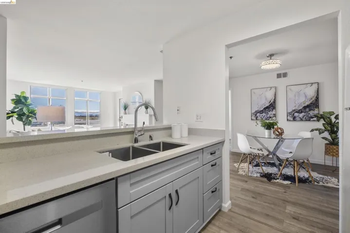 Kitchen with light gray shaker cabinetry, stainless steel double basin sink, and light-toned countertops
