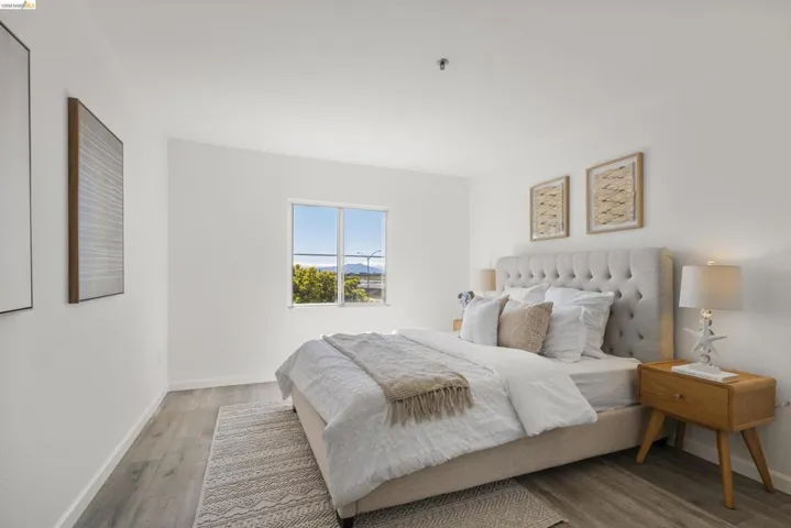 Spacious room featuring light wood-finish flooring, white walls, and a large window