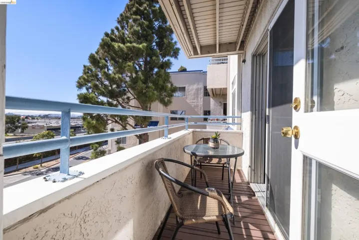 Private balcony featuring wood-finish flooring, a white textured wall, and a blue metal railing