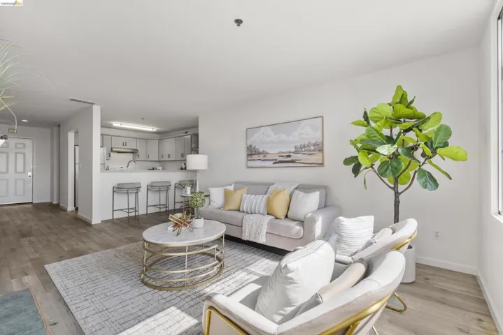 Open-concept living area featuring wood-finish flooring, a kitchen pass-through with breakfast bar, recessed lighting, and a white paneled entry door