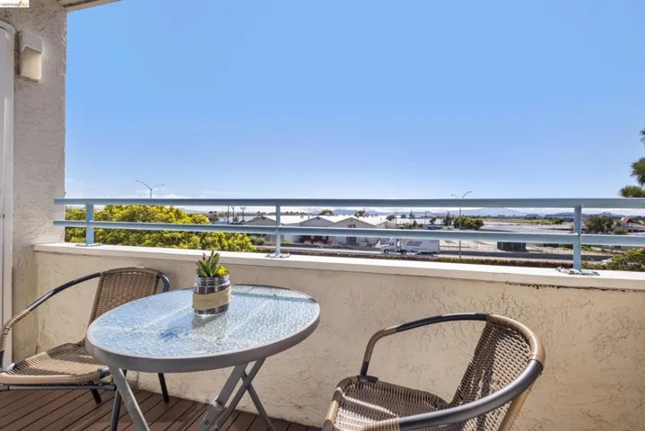 Private balcony featuring a stucco wall, blue metal railing, and wood-finish flooring
