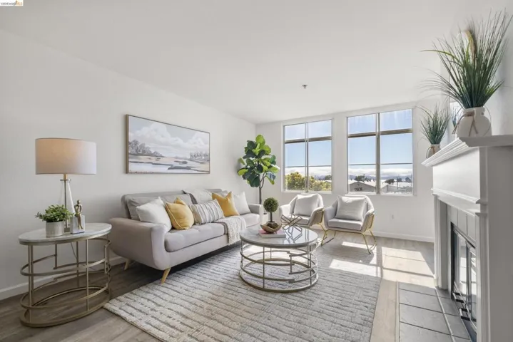 Living area featuring multiple windows, wood-finish flooring, a white fireplace with a mantel, and a neutral color palette