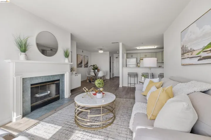 Living area featuring a fireplace with a white mantel and tiled surround, wood-finish flooring, and light-toned walls