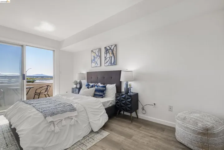 Bedroom featuring a sliding glass door leading to an outdoor balcony, wood-finish flooring, and a tufted headboard