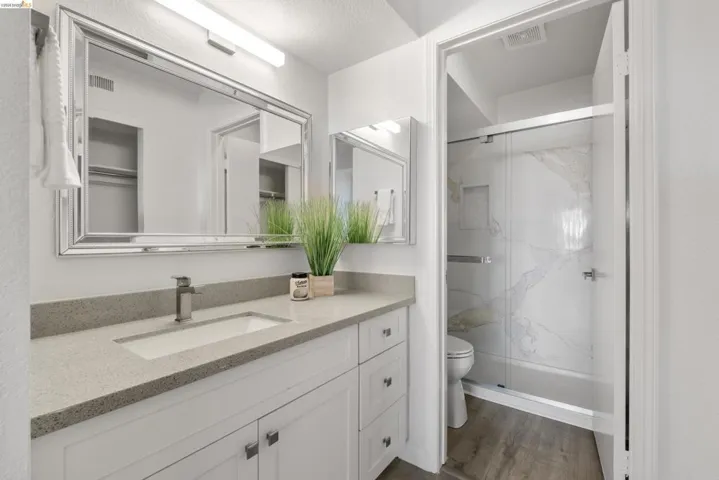 Bathroom featuring a white vanity with shaker-style cabinetry, a light-colored countertop, and an integrated rectangular sink