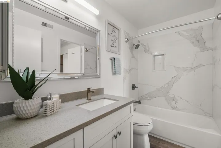 Bathroom featuring a white vanity with a gray stone-finish countertop, integrated sink, and bronze-finish faucet