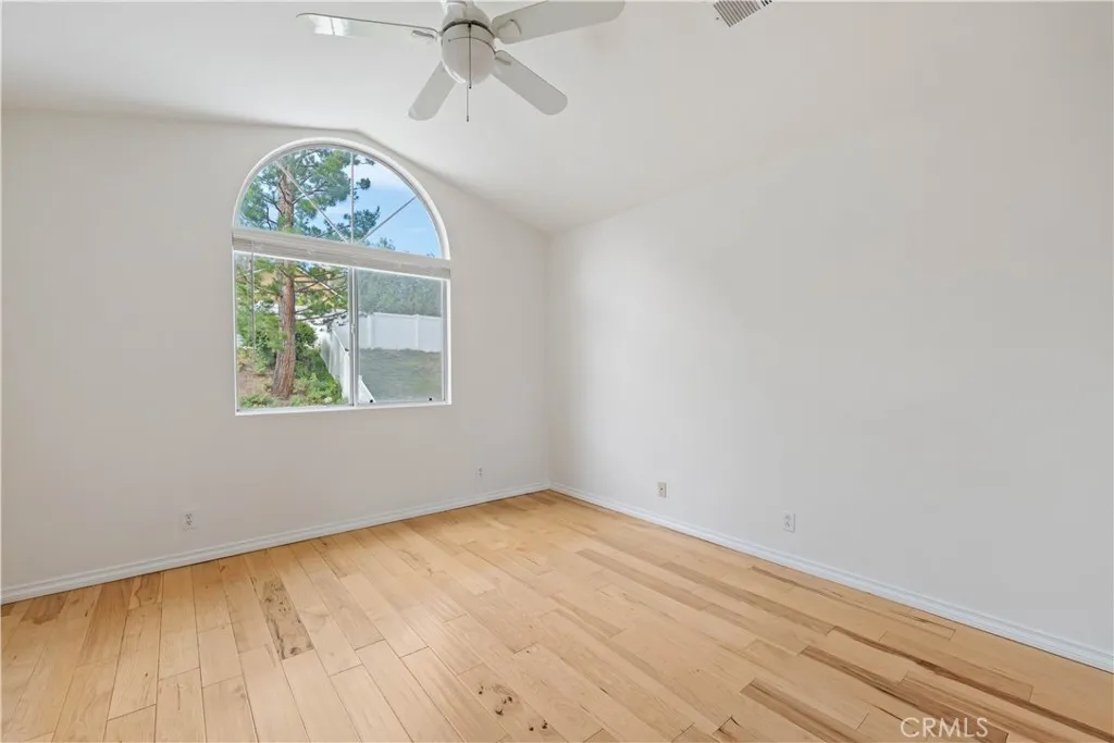 Primary bedroom with ceiling fan, vaulted ceiling & views of the yard