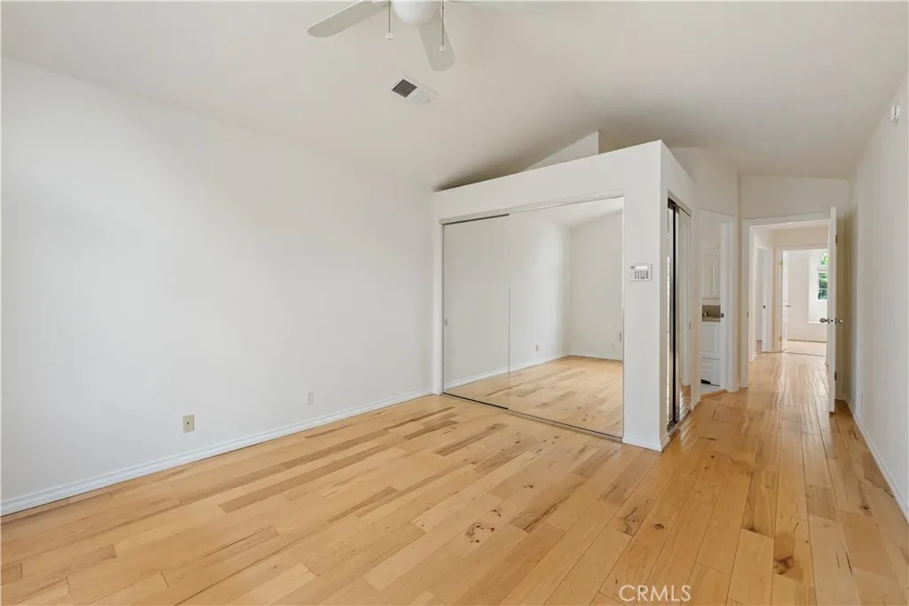 Primary bedroom with wood floors, 2 double door mirrored wardrobe closets with built-ins.
