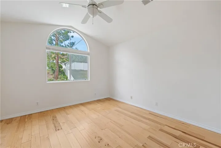 Primary bedroom with ceiling fan, vaulted ceiling & views of the yard