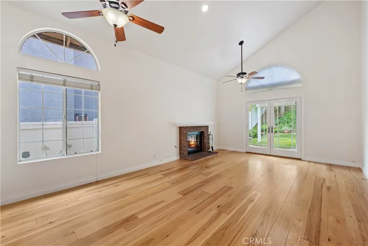 Living room and dining area with wood floors, a ceiling fan & French doors.
