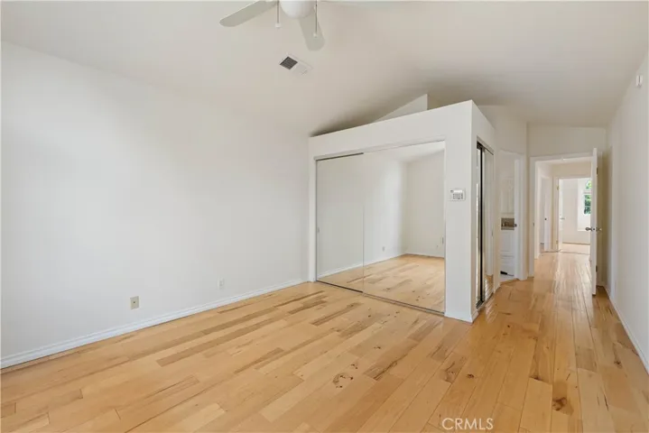 Primary bedroom with wood floors, 2 double door mirrored wardrobe closets with built-ins.