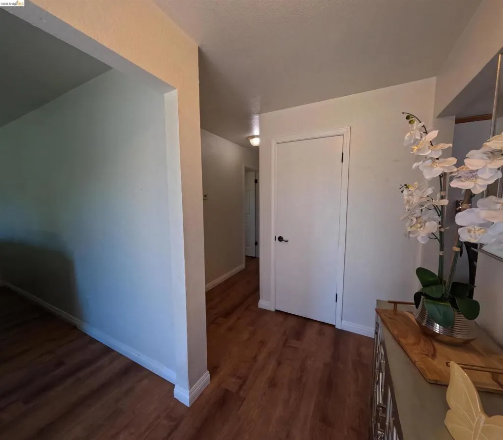 Hallway with wood-finish flooring, white baseboards, and a recessed light fixture