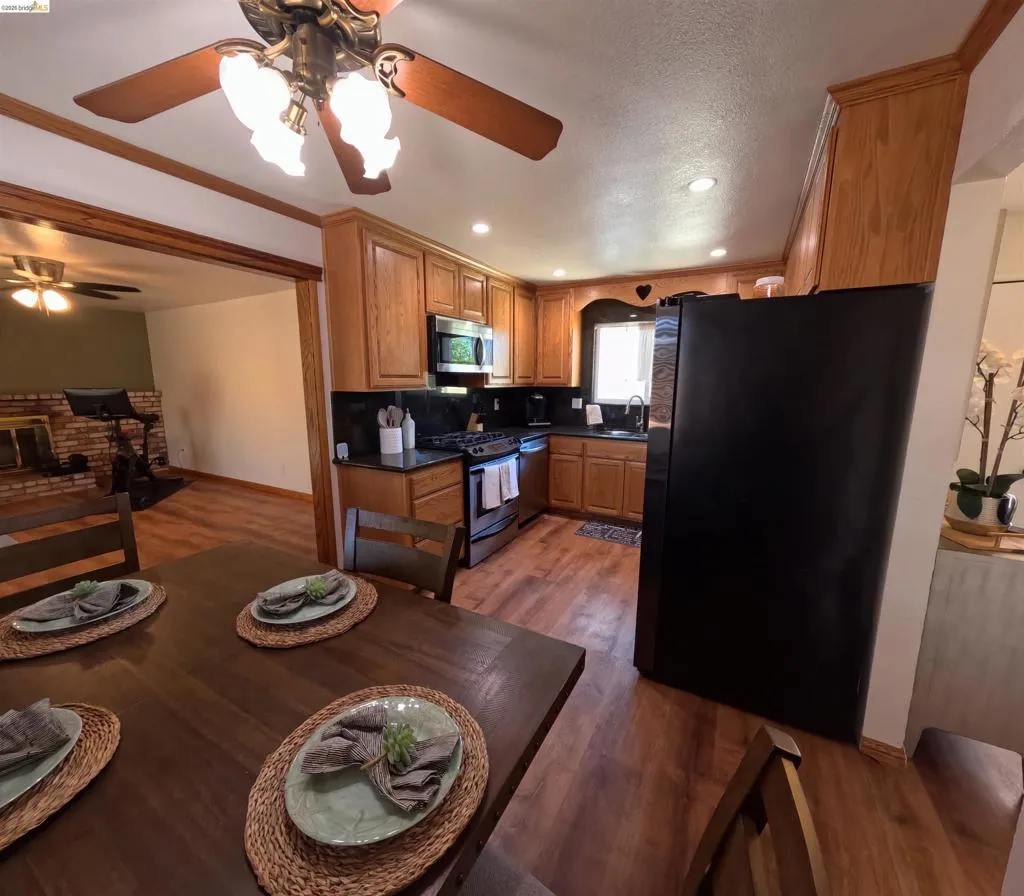 Kitchen featuring wood-finish flooring, recessed lighting, wood cabinetry, dark countertops, and stainless steel appliances
