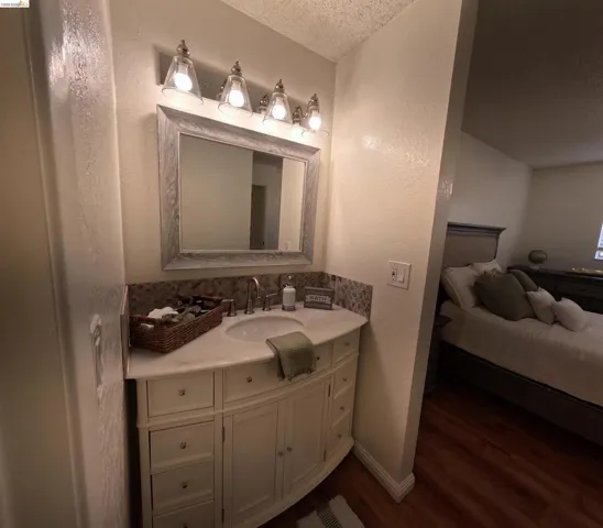 Curved vanity with white finish, integrated sink, and stone countertop