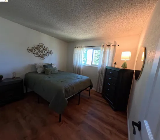 Spacious room featuring wood-finish flooring, a window with natural light, and ample wall space