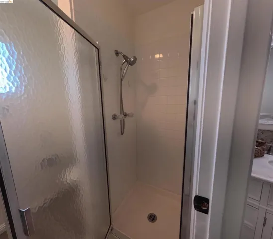 Shower enclosure featuring a textured glass door, white subway tile surround, and a chrome shower fixture