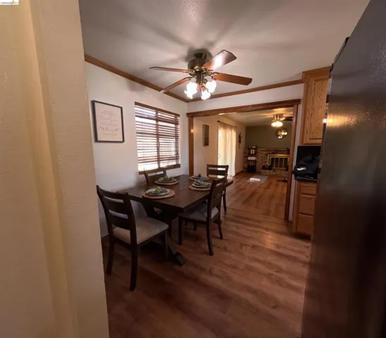Dining area featuring wood-finish flooring, a ceiling fan with integrated lighting, and a window with horizontal blinds