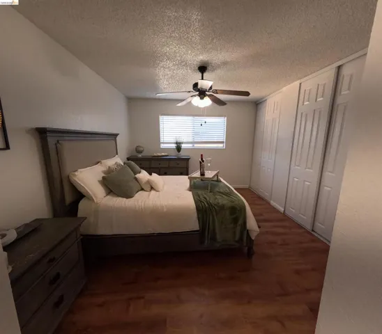 Bedroom featuring wood-finish flooring, a ceiling fan with integrated lighting, and a window with horizontal blinds