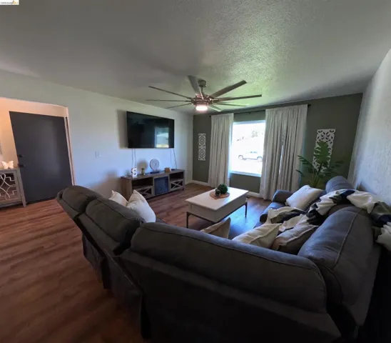 Living area featuring wood-finish flooring, a contemporary ceiling fan with integrated lighting, and a multi-tone wall palette