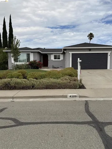 Single-story residence featuring a gray exterior, dark garage door, and a red entry door