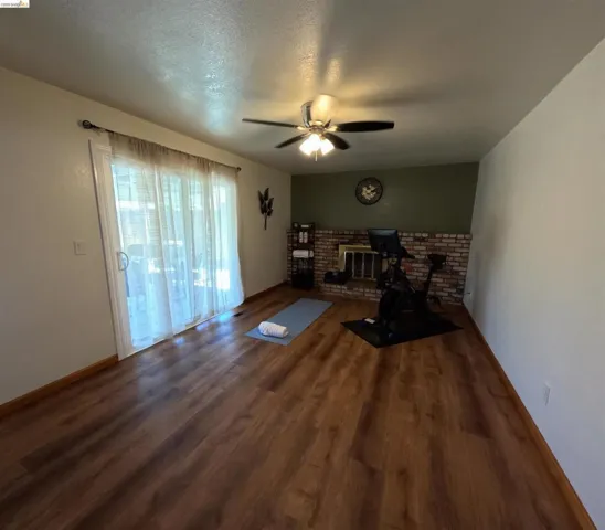 Spacious room featuring wood-finish flooring, a brick fireplace, and sliding glass doors