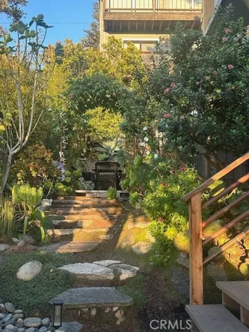 Inside the front garden, the stairs on the right go to front door, and the garden continues to back with table & chairs.
