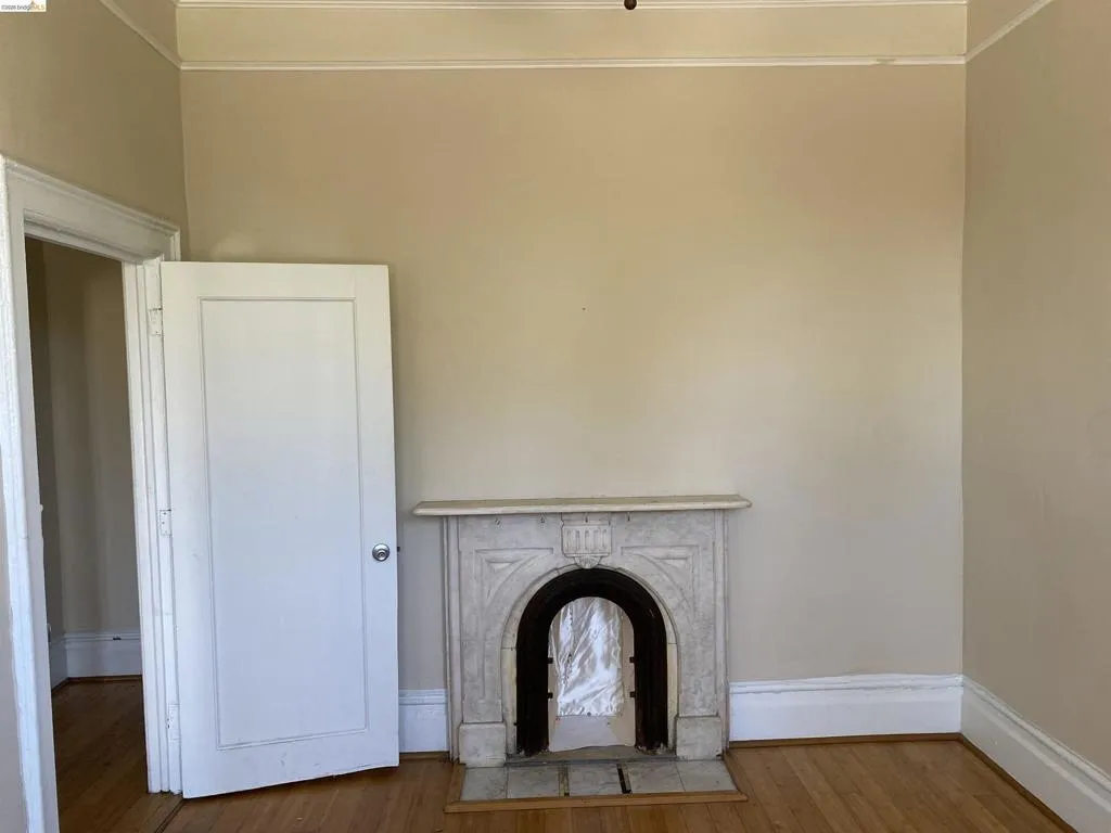 Classic fireplace with a decorative mantel, hardwood flooring, and crown molding