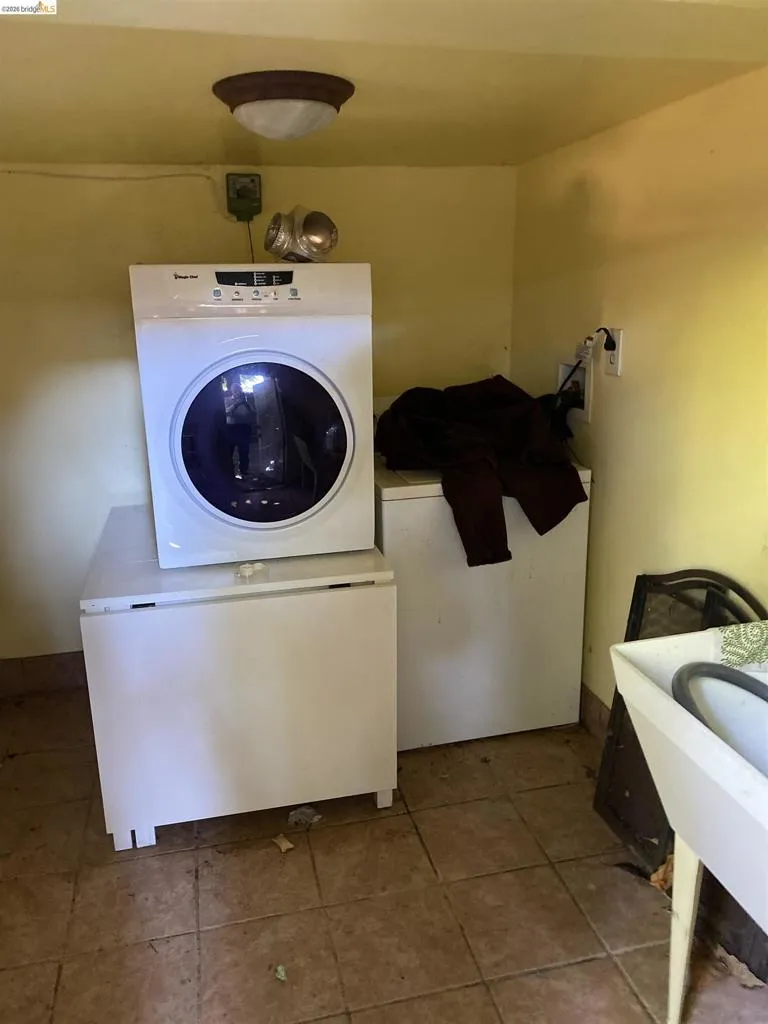 Utility room featuring a white laundry sink, ceramic tile flooring, and a flush-mount ceiling light