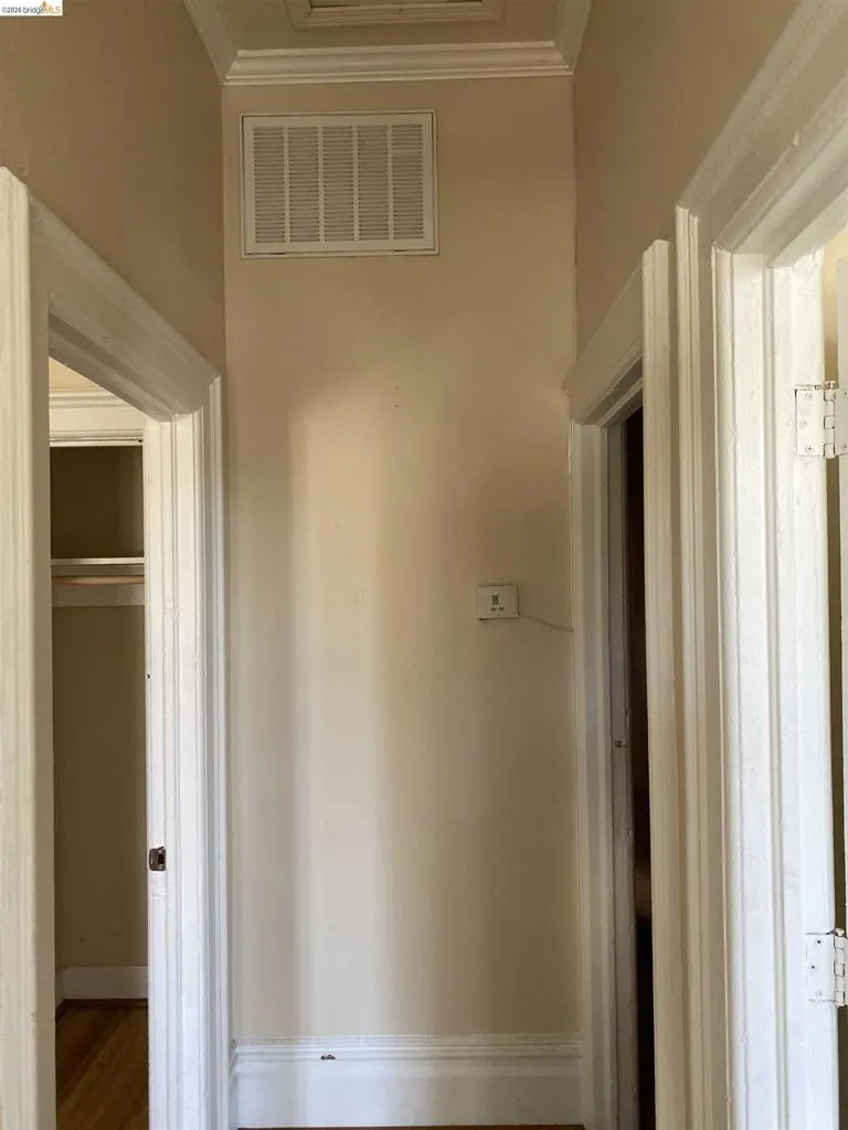 Hallway featuring crown molding and baseboards, light-toned walls, and multiple doorways with trim