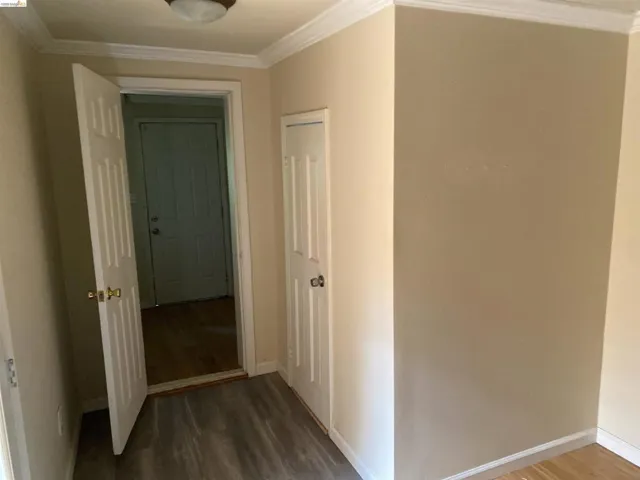Interior space featuring light-toned walls, crown molding, and wood-finish flooring