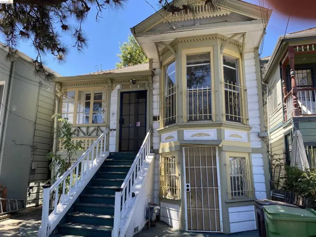 Victorian-style facade featuring an ornate bay window, detailed spindle work, a covered porch, and a dedicated exterior staircase