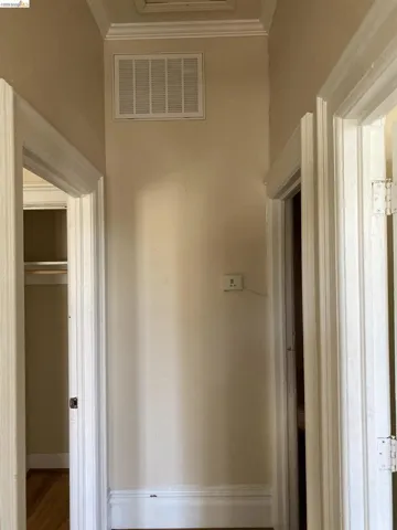 Hallway featuring crown molding and baseboards, light-toned walls, and multiple doorways with trim