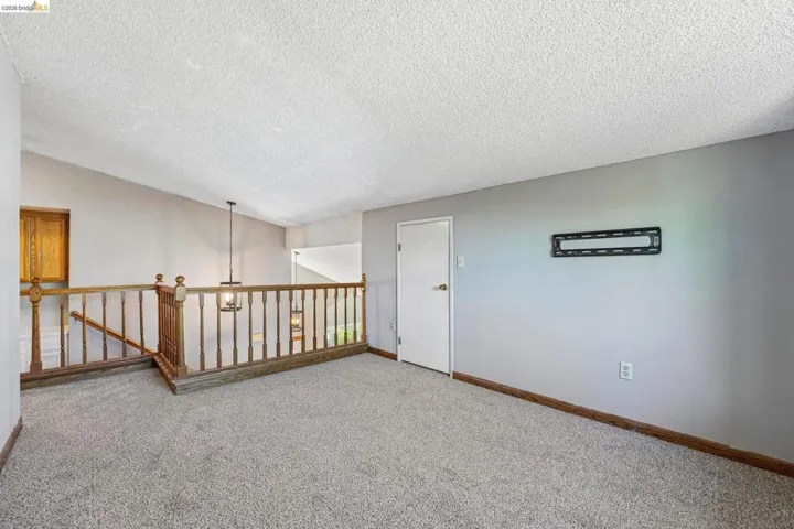 Carpeted open loft area featuring wood railing, light gray wall paint, and white trim