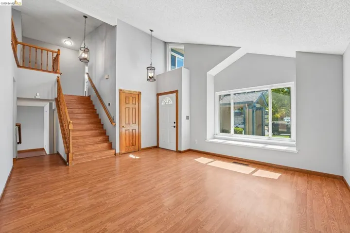 Vauted entryway with wood-finish flooring, a wood staircase, and a large window with a deep sill